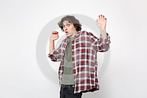 Portrait of shocked scared young man in casual clothes looking camera, rising hands showing palms isolated on white