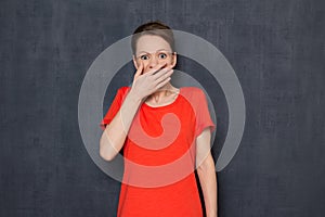 Portrait of shocked scared young woman covering mouth with hand