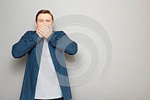 Portrait of shocked stunned mature man covering mouth with hands