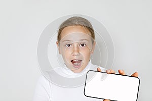 Portrait of shocked surprised excited child girl with smart phone with big blank empty white screen display