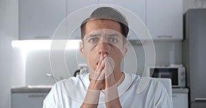 Portrait of shocked and surprised man sits on sofa at home. Astonished man scared by the news looks at the camera on