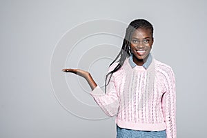 Portrait of shocked woman holding copyspace on palm looking at camera isolated on grey background