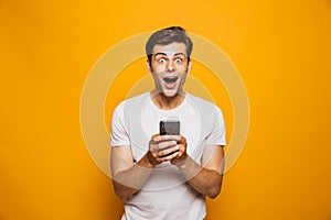 Portrait of a shocked young man holding mobile phone