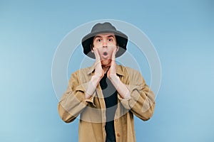 Portrait of shocked young man in panama and shirt with surprised face looking at camera and raised his hands a handful of shock,