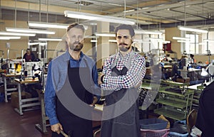 Portrait of shoe factory worker standing together looking at camera at workshop