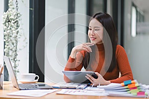 Portrait shot of asian businesswoman hands holding and using digital tablet, sitting at her desk.