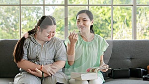 Portrait shot of Asian lovely mother sitting on floor and young chubby down syndrome autistic autism little daughter lay down on