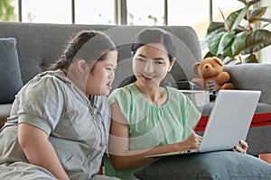 Portrait shot of Asian lovely mother sitting on floor and young chubby down syndrome autistic autism little daughter lay down on