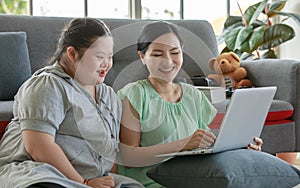 Portrait shot of Asian lovely mother sitting on floor and young chubby down syndrome autistic autism little daughter lay down on