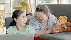 Portrait shot of Asian lovely mother sitting on floor and young chubby down syndrome autistic autism little daughter lay down on