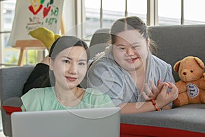 Portrait shot of Asian lovely mother sitting on floor and young chubby down syndrome autistic autism little daughter lay down on