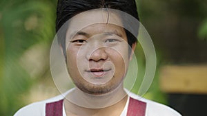 Portrait shot of an Asian man staring at the camera smiling