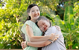 Portrait shot of Asian mother and young chubby down syndrome autistic autism little cute girl with braid pigtail hairstyle stand