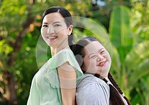 Portrait shot of Asian mother and young chubby down syndrome autistic autism little cute girl with braid pigtail hairstyle stand