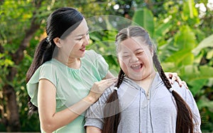 Portrait shot of Asian mother and young chubby down syndrome autistic autism little cute girl with braid pigtail hairstyle stand