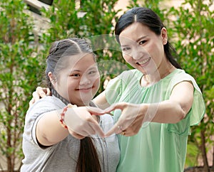 Portrait shot of Asian mother and young chubby down syndrome autistic autism little cute girl with braid pigtail hairstyle stand