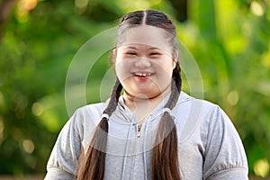 Portrait shot of Asian young chubby down syndrome autistic autism little cute schoolgirl with braid pigtail hairstyle model stand