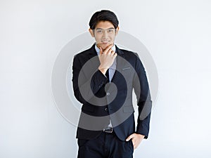 Portrait shot of Asian young handsome happy intelligence successful businessman in black formal suit stand hold hand touch chin