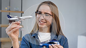 Portrait shot of attractive young woman with toy plane and car in the hands.