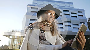 Portrait shot of cute blonde hair girl chatting with someone using her tablet while relaxing on the grass.