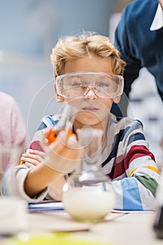 Portrait Shot of a Cute Little Boy with Safety Glasses Mixes Chemicals in Beakers. Elementary School