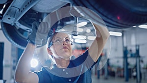 Portrait Shot of a Female Mechanic Working Under Vehicle in a Car Service. Empowering Woman Wearin