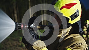 Portrait shot of the firefighter spraying fire with the hose. Close up