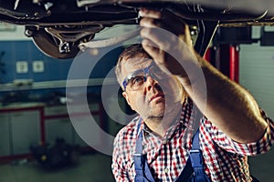 Portrait Shot of a Handsome Mechanic Working on a Vehicle in a Car Service
