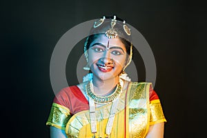 Portrait shot happy smiling Indian Bharatnatyam dancer on stage looking at camera - concept of classical dance