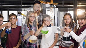 Portrait shot of Korean science man teaching young students doing chemical experiment, children holding flasks with