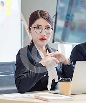 Portrait shot of Millennial Asian young professional successful female businesswoman in formal suit with eyeglasses sitting