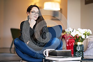 Relaxed young woman with beautiful smile sitting on the chair in the living room