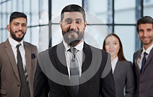 portrait shot of smiling business team of four standing and smiling at camera against a modern office background