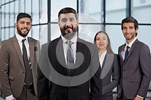 portrait shot of smiling business team of four standing and smiling at camera against a modern office background