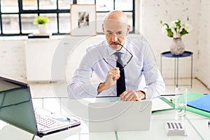 Portrait shot of stressed businessman working on laptop at the office