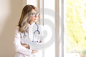 Thinking female doctor looking out the window photo