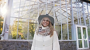 Portrait shot of young beautiful woman in sunglasses looking to the camera and smiling on the park background.