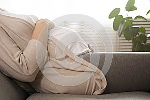 Portrait shot of young beautiful woman on third trimester of pregnancy. Close up of pregnant female with arms on her round belly.