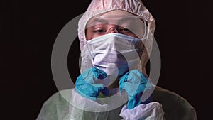 portrait shot of young female doctor in white protective uniform. puts on a medical mask on the face. The concept of