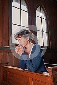 Young woman with closed eyes praying in the church