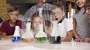 Portrait shotting of group of caucasian school children in chemical lab. Pupils putting dry ice into the flasks with