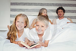 Portrait of siblings relaxing with parents on bed