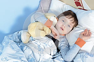 Portrait of a sick boy hugging a teddy bear