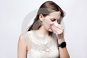 Portrait of sick cold woman with freckles and white dress and smart watch on silver gray background.