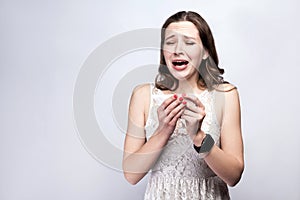 Portrait of sick cold woman with freckles and white dress and smart watch on silver gray background.