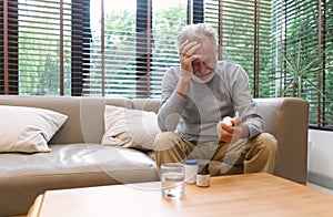 Portrait of a sick elderly man feeling sick ill suffering from headache. He taking antibiotic antidepressant painkiller pill