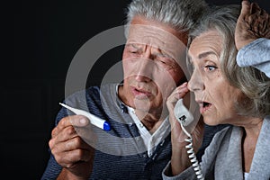Portrait of sick elderly woman and man calling doctor