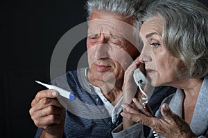 Portrait of sick elderly woman and man calling doctor