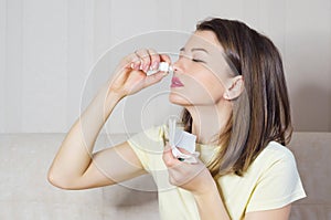 Portrait of sick girl with runny nose, rhinitis, allergies, colds. woman holds medical spray in hand.