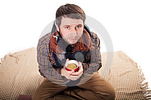 Portrait of a sick man with the flu coughing and holding a warm tea cup